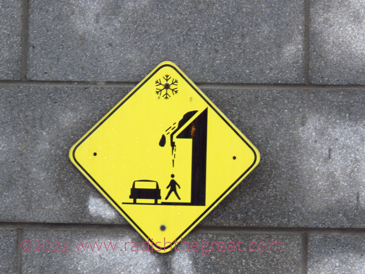 sign showing snow falling off a roof onto a person